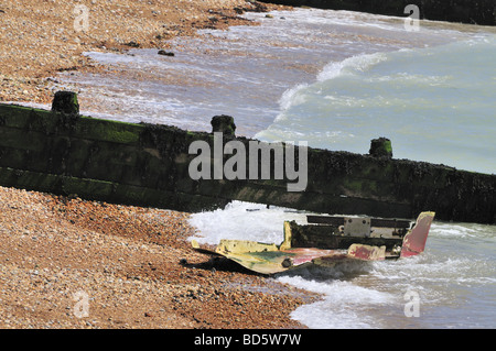 Kleines zerstörten Ruderboot, Schindel neben einem hölzernen Wellenbrecher angespült Stockfoto
