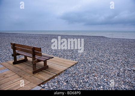 Holzbank an einem Kiesstrand an einem bewölkten Tag Stockfoto