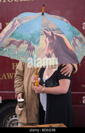 Schlechtes Wetter im August Rian in Großbritannien. Menschen, die unter einem dekorierten Pferdeschirm auf der Brigg Horse Fair, Lincolnshire, 2009 2000er, UK HOMER SYKES, Schutz bieten Stockfoto