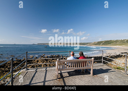 ein paar sitzt auf einer Bank, Blick auf das Meer in Sennen Cove cornwall Stockfoto