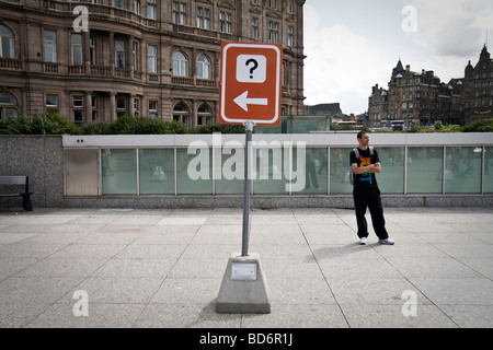 Ein Schild mit einem Fragezeichen und Pfeil nach links - im Hintergrund sieht ein Mann rechts Stockfoto