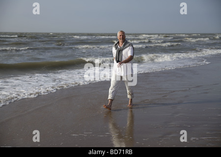 Männlichen Best Ager zu Fuß am Strand der Nordsee in De Haan, Belgien Stockfoto