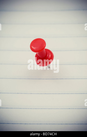 Rote Reißzwecke in Papier Stockfoto