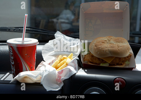 KFC Burger Pommes und Cola auf dem Armaturenbrett eines Autos van dem schnellen Fastfood Mittagessen Stockfoto