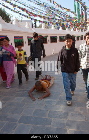 Bodhnath, Nepal.   Eine buddhistische Anhänger sucht Verdienst, Segen und Vergebung durch einkreisen der Stupas in einer Reihe von Niederwerfungen. Stockfoto