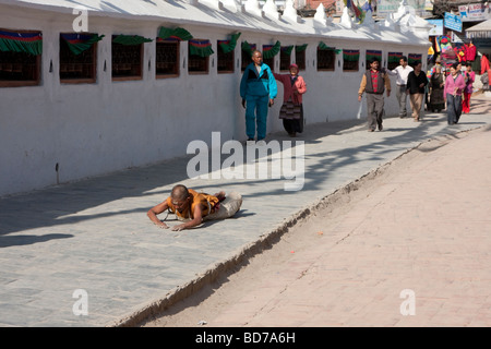 Bodhnath, Nepal.   Eine buddhistische Anhänger sucht Verdienst, Segen und Vergebung durch einkreisen der Stupas in einer Reihe von Niederwerfungen. Stockfoto