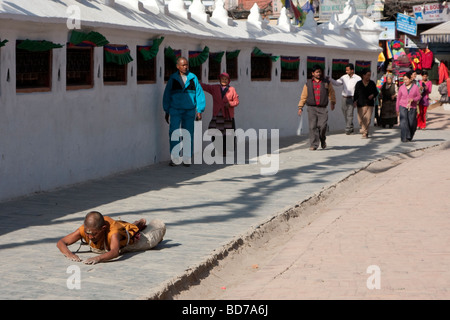 Bodhnath, Nepal.   Eine buddhistische Anhänger sucht Verdienst, Segen und Vergebung durch einkreisen der Stupas in einer Reihe von Niederwerfungen. Stockfoto