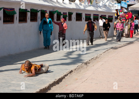 Bodhnath, Nepal.   Eine buddhistische Anhänger sucht Verdienst, Segen und Vergebung durch einkreisen der Stupas in einer Reihe von Niederwerfungen. Stockfoto