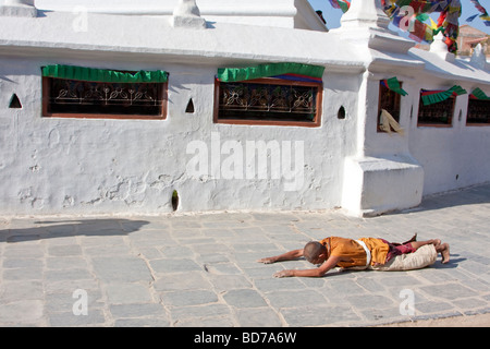 Bodhnath, Nepal.   Eine buddhistische Anhänger sucht Verdienst, Segen und Vergebung durch einkreisen der Stupas in einer Reihe von Niederwerfungen. Stockfoto