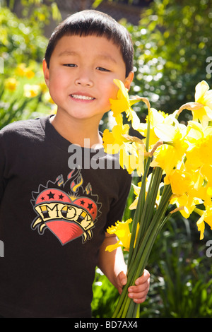 Boy Holding Narzissen im Garten Stockfoto