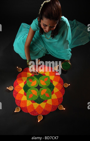 erhöhte Ansicht einer jungen Frau, die Verzierung Rangoli mit Öllampen Stockfoto