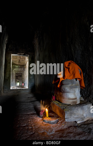 Eine Buddha-Statue in einen Korridor von Angkor Wat mit Weihrauch und eine Kerze brennen Stockfoto