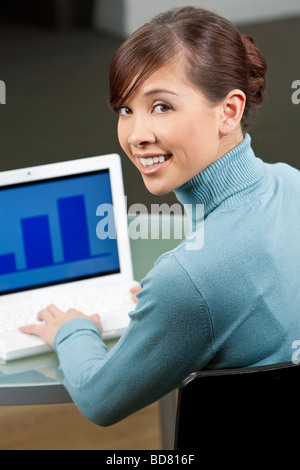 Eine schöne junge orientalische Frau mit einem wunderbaren toothy Lächeln mit einem Laptop in ihrem Büro Stockfoto