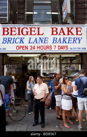 Leute Essen am Sonntag vor berühmten Bagel Backen Bäckerei auf der Brick Lane Market Day. Dies ist der berühmteste Bagel-Shop in London. Stockfoto