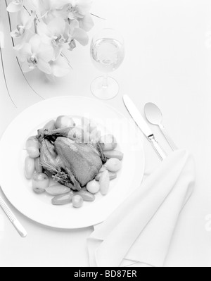 Ein Gedeck mit einem Perlhuhn und Blumen in schwarz und weiß Stockfoto