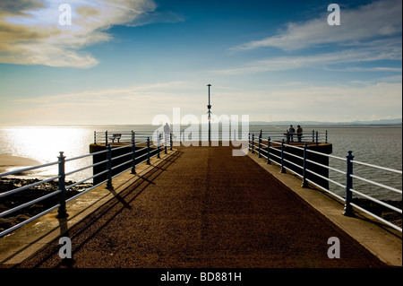 Silhouettenfiguren am Ende der Stone Jetty, Morecambe Bay bei Sonnenuntergang. VEREINIGTES KÖNIGREICH Stockfoto