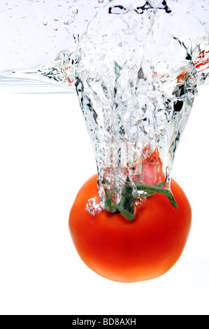 Rote Tomate spritzt ins Wasser über einen weißen Hintergrund Stockfoto