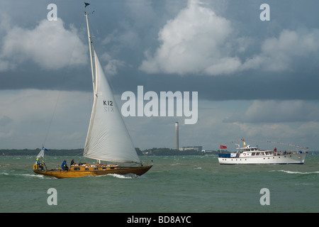 Hölzerne Yacht vorbei einen Kabinenkreuzer auf dem Solent angesehen von der Esplanade Cowes Isle Of Wight England Stockfoto