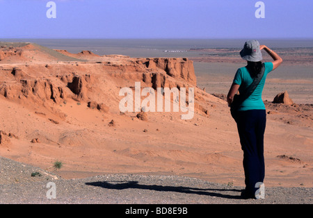 Touristen, die gerade des Panoramas auf die rote Erde Bayanzag flammenden Klippen, aka Dinosaurier Friedhof, Wüste Gobi, Mongolei Stockfoto