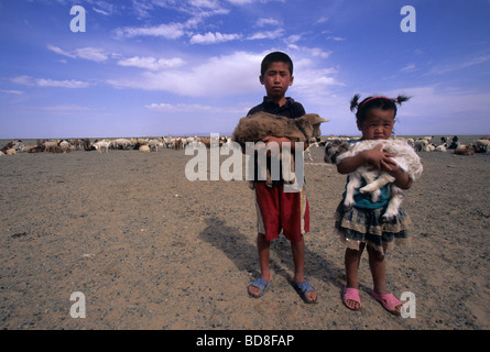 Mongolische Kinder halten ein Lamm in den Armen, Mongolei Stockfoto