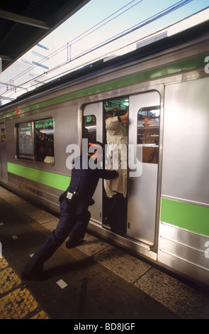 Menschen immer geschoben und schob in u-Bahn Zug Tür während der Hauptverkehrszeit Tokio Stockfoto