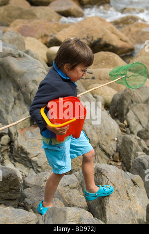 Jungen mit Netzen und Eimer gehen "Rockpooling" an der Küste in der Nähe von Mousehole, Cornwall Stockfoto