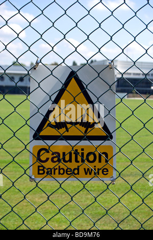 Vorsicht Stacheldraht Schild an einem Zaun in Chiswick Polytechnischen Stadion, Chiswick, West London, england Stockfoto