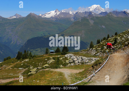 Ein downhill Mountainbiker springt um eine Ecke mit dem Mont Blanc im Hintergrund in Les Arcs, Frankreich. Stockfoto