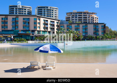 Sonnenliegen und Sonnenschirme neben dem Wave Lagune und Hotels in Darwin Waterfront Precinct. Australien Stockfoto