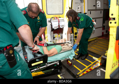 Sanitäter, die Beantwortung von ein 999 anrufen setzen ältere Dame, die zu Hause auf einer Bahre in gefallen hat und ihr ins Krankenhaus Stockfoto