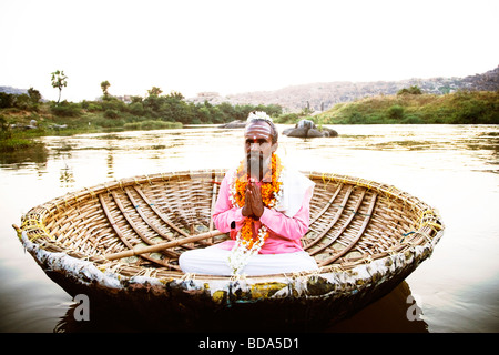 Sadhu Anbetung in einem Coracle Tungabhadra Fluss, Hampi, Karnataka, Indien Stockfoto