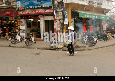 Eine Frau mit einem traditionellen konischen Hut geht durch die Altstadt von Hanoi Vietnam Stockfoto