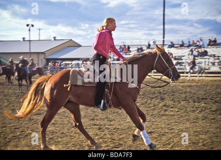 Junge Frau auf dem Pferd in der Arena der Kirmes Beurteilung Stockfoto