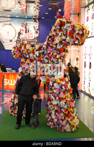 Vater und Sohn posieren vor einem riesigen Hund aus Blumen im Swatch Store am Times Square, New York, Vereinigte Staaten. Stockfoto