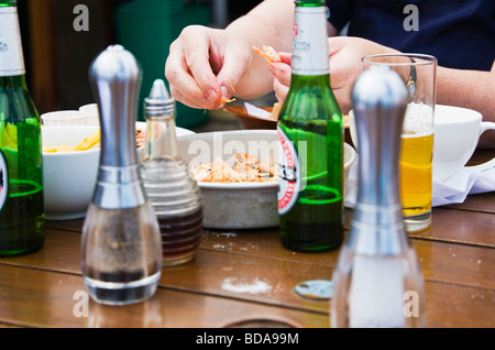 Frau schälen Garnelen zur Mittagszeit. Verzehr von Meeresfrüchten in einem Outdoor-Restaurant in der Stadt am Meer von Swanage, Dorset. VEREINIGTES KÖNIGREICH. Stockfoto