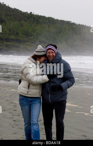 Paar Lachen und Lächeln bei einem Spaziergang entlang des Strandes in der Nähe von Tofino, BC Stockfoto