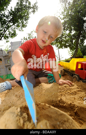 Baby junge Jungen in Sand Grube spielen mit Spaten und Spielzeug Auto Autos Fahrzeug Spielplatz 2 3 4 Jahre Stockfoto