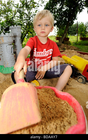 Baby junge Jungen in Sand Grube spielen mit Spaten und Spielzeug Auto Autos Fahrzeug Spielplatz 2 3 4 Jahre Stockfoto