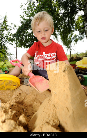 Baby Kind junge Jungen in Sand Grube spielen mit Spaten und Spielzeug Auto Autos Fahrzeug Spielplatz 2-3-4 Jahre Stockfoto