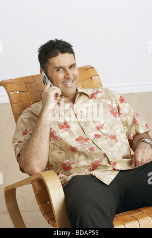 Porträt eines Mitte erwachsenen Mannes auf einem Stuhl sitzend und am Telefon sprechen Stockfoto