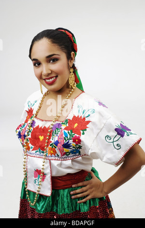 Porträt einer jungen Frau in typischen mexikanischen Tracht stehen mit der Hand auf ihre Hüfte und lächelnd Stockfoto