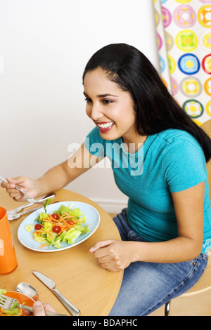 Junge Frau an einem Tisch sitzen und essen Salat Stockfoto