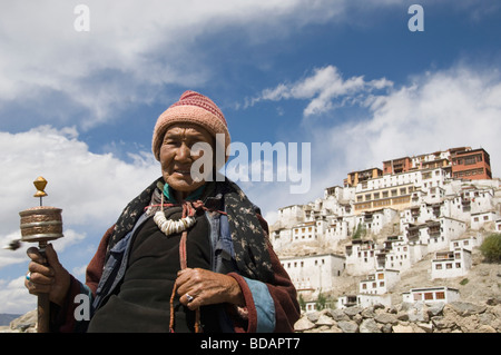 Frau beten mit Kloster im Hintergrund Thikse Kloster, Ladakh, Jammu und Kaschmir, Indien Stockfoto