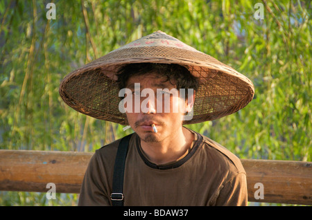 Portrait Mann raucht Zigarette und einen großen konischen Hut antiken Stadt Fenghuang Hunan China Stockfoto