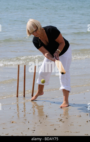 Frau spielt Cricket am Meer im Ruhestand genießen gesunden Bewegung am Strand Stockfoto