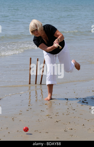 Frau spielt Cricket am Meer im Ruhestand genießen gesunden Bewegung am Strand Stockfoto