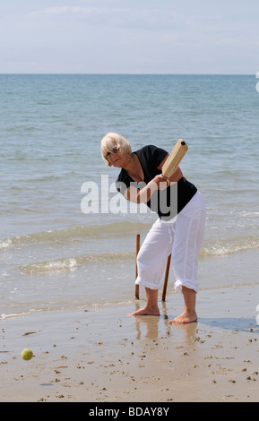 Frau spielt Cricket am Meer im Ruhestand genießen gesunden Bewegung am Strand Stockfoto