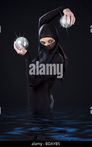 Partei-Tänzerin in Ninja-Kleid mit Disco-Kugeln Stockfoto