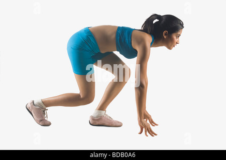 Seitenansicht einer jungen Frau in Bereitposition hocken Stockfoto