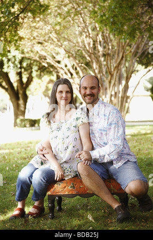 Porträt eines Mitte erwachsenen Mannes und eine reife Frau sitzt auf einem Stuhl in einem Rasen Stockfoto